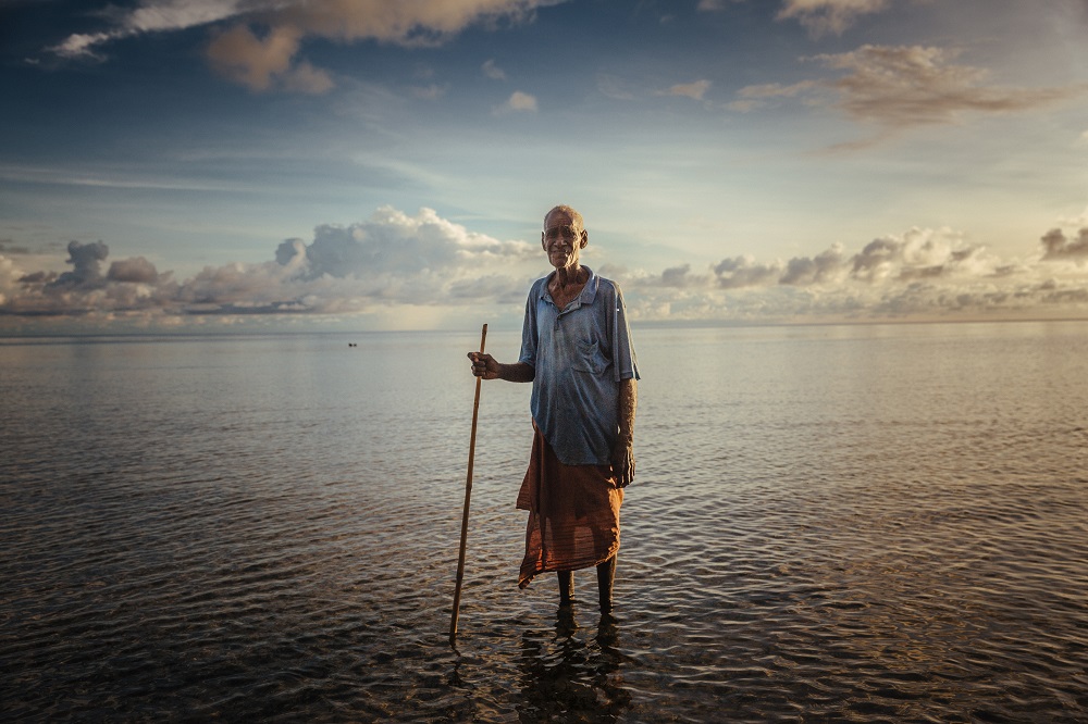 An elderly man poses on one of the atolls of the Carteret islands. Photo: IOM / Muse Mohammed 2016